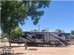 Large trailer parked on gravel site at ENCHANTED TRAILS RV PARK & TRADING POST - thumbnail