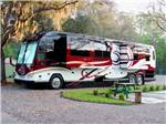 Large black, red and white RV with pop outs extended alongside green picnic table at HIGHBANKS MARINA & CAMPRESORT - thumbnail