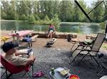 People in a campsite by the water at WHISPERING PINES RV CAMPGROUND - thumbnail