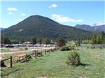Line of picnic tables with RVs and hill in background at ELK MEADOW LODGE AND RV RESORT - thumbnail