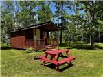 A red picnic table in front of a rental cabin at BORDEN/SUMMERSIDE KOA - thumbnail