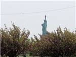 Statue of Liberty viewed over trees at LIBERTY HARBOR MARINA & RV PARK - thumbnail
