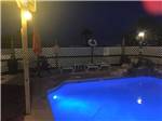 Lit public swimming pool with fountain in corner at night at SEA BREEZE RV COMMUNITY RESORT - thumbnail