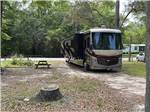 A motorhome in a sandy RV site at RIVERS EDGE RV CAMPGROUND - thumbnail