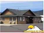 Outdoor seating for 2 in front of a brown and green building at SUSANVILLE RV PARK - thumbnail