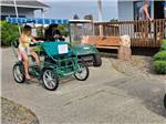 Two kids riding a surrey on a path at OSPREY POINT RV RESORT - thumbnail