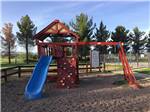 Brightly colored red and blue playground with climbing wall and swing set at LOST ALASKAN RV PARK - thumbnail
