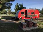 Red trailer parked behind brick table at LOST ALASKAN RV PARK - thumbnail