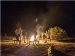 A group of people standing around a fire at night at STAGECOACH TRAILS RV PARK - thumbnail