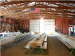 Dining hall with many wooden tables and benches adorned in shabby chic decor at COZY ACRES CAMPGROUND/RV PARK - thumbnail