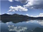 Forested hill and sky reflected in lake at EAGLE LAKE RV PARK - thumbnail