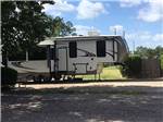 Fifth-wheel parked against a blue sky at WOODLAND LAKES RV PARK - thumbnail