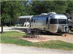 Airstream trailer parked near table and chairs at WOODLAND LAKES RV PARK - thumbnail