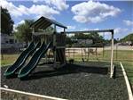 Swing set attached to play structure with slide at WOODLAND LAKES RV PARK - thumbnail