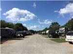 Campground road flanked by campsites under blue sky  at WOODLAND LAKES RV PARK - thumbnail