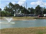 Pond with fountain and RVs on the banks at WOODLAND LAKES RV PARK - thumbnail