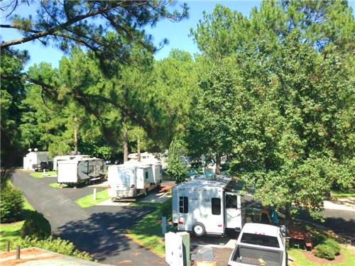 White travel trailers camping at campsite and green trees at AMERICAN HERITAGE RV PARK