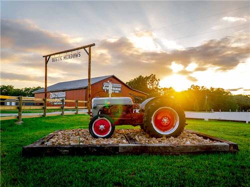 Antique tractor and barn at park entrance at RUSTIC MEADOWS RV PARK