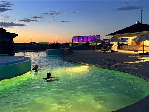 Two people in the swimming pool at night at ROUTE 66 RV RESORT