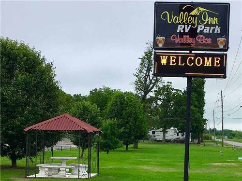 Sign at park entrance with covered seating area at VALLEY INN RV PARK