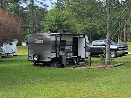A travel trailer in a grassy site at HEAVENLY WATERS RV PARK