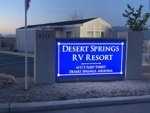 The front entrance sign lit up at night at DESERT SPRINGS RV RESORT