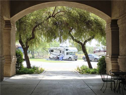 A family sitting on the side of their RV in a concrete site at BAKERSFIELD RIVER RUN RV PARK