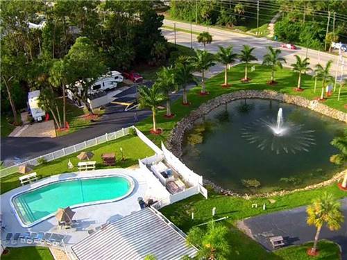 Aerial view of large pond with fountain, community pool and lush landscaping at BONITA LAKE RV RESORT