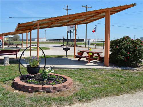 Bench and fire pit under a pavilion at ABILENE RV PARK