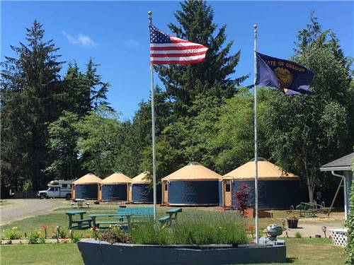 A sailboat with flags in front of five yurts at TILLAMOOK BAY CITY RV PARK