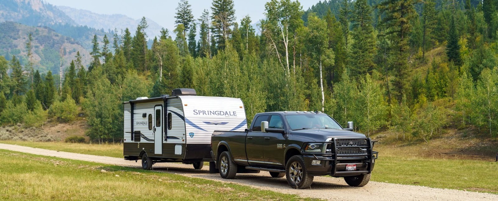 Dodge RAM pickup truck towing a Springdale fifth wheel camper on a mountain road