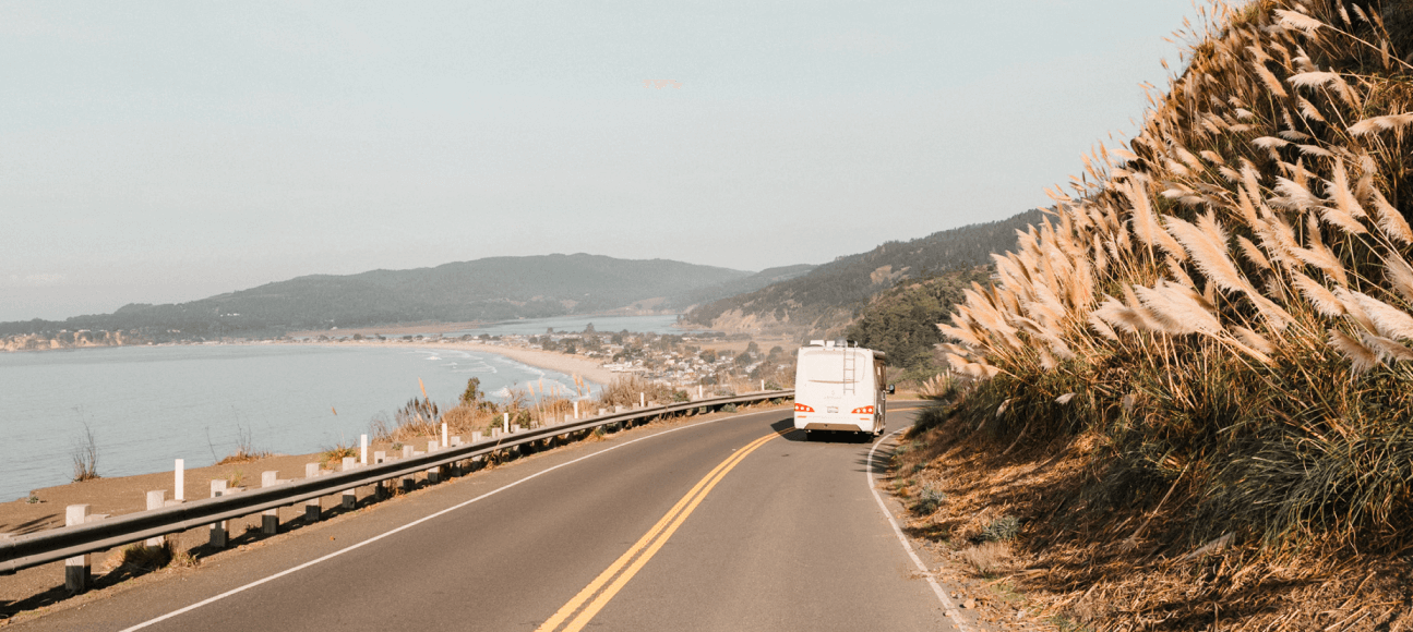 RV driving on road next to beach