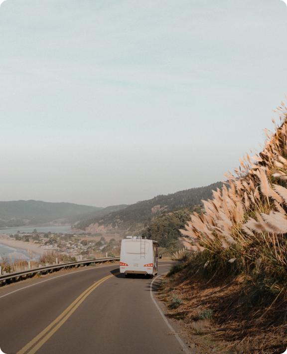 RV driving on road next to beach