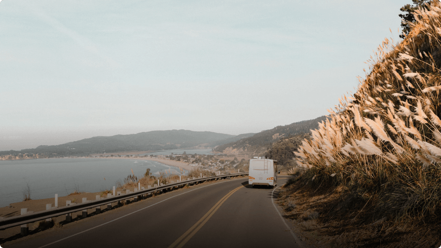 RV driving on road next to beach