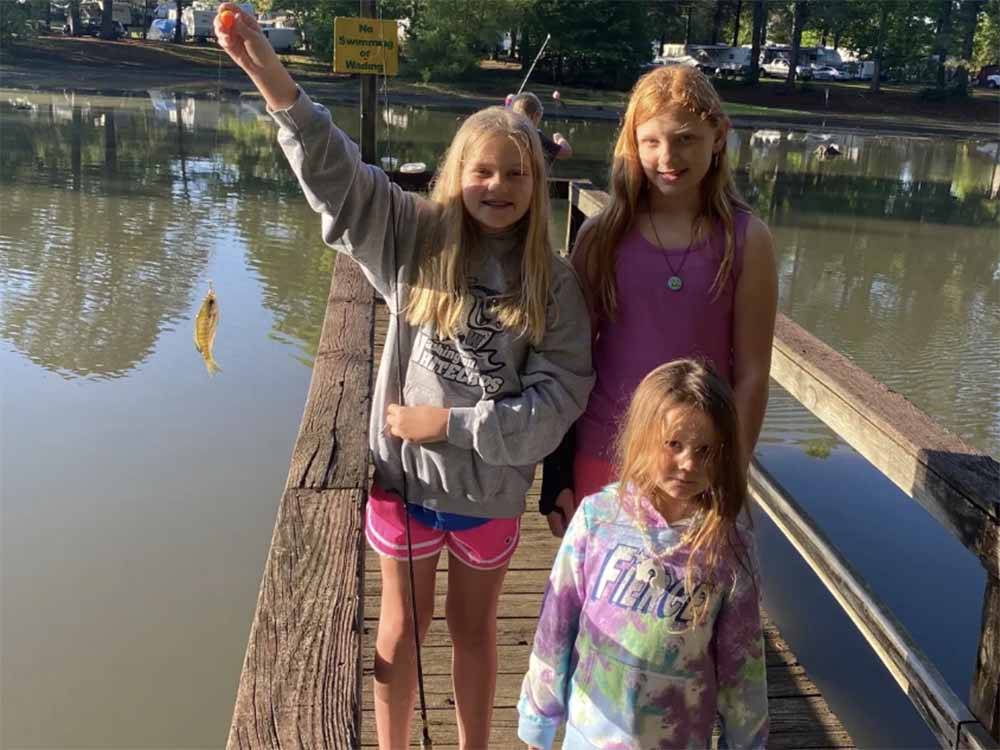 Three girls on the pier and one showing her fish at GREEN ACRES FAMILY CAMPGROUND