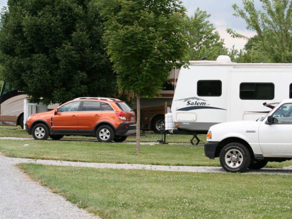 A travel trailer and vehicles parked at site at Indiana Beach Campground