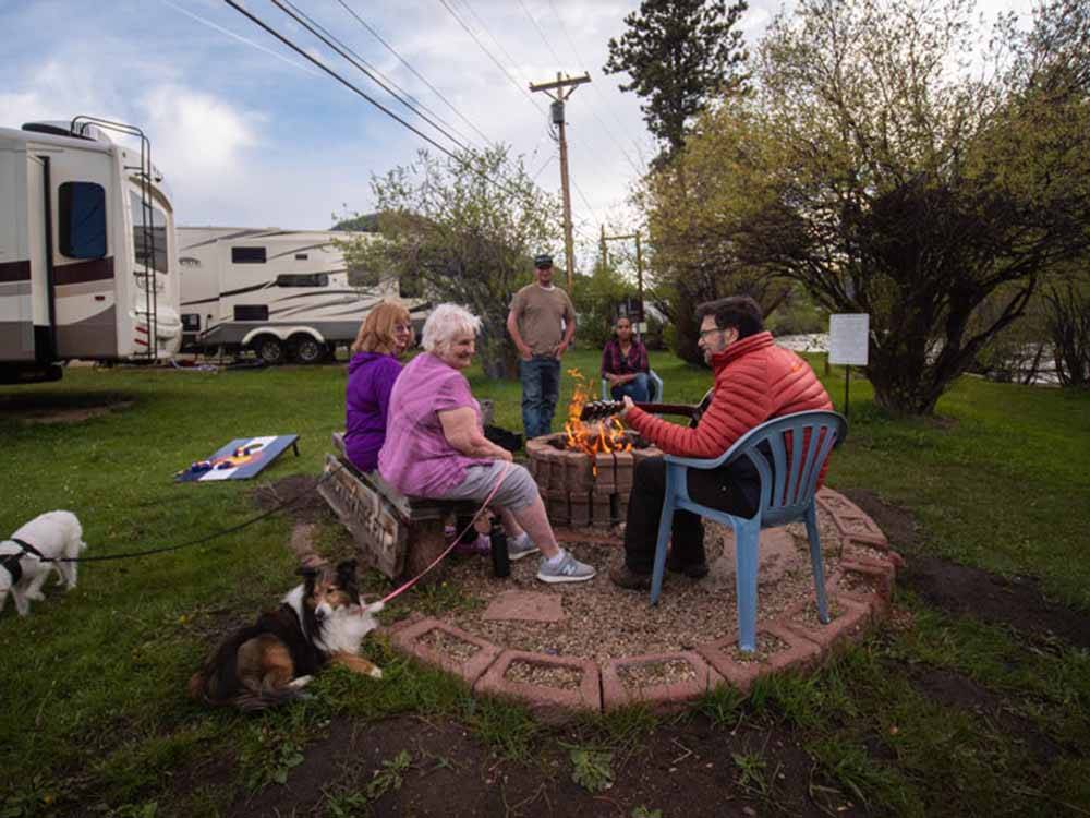 People around a fire pit with a dog at MANOR RV PARK