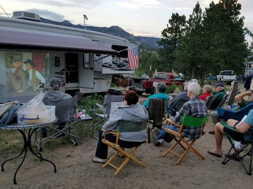 A group of people watching a movie on the side of a motorhome at MANOR RV PARK