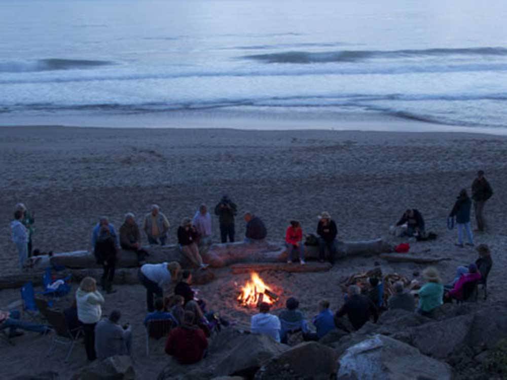 Group of people gathering for bonfire at beach at SEA & SAND RV PARK