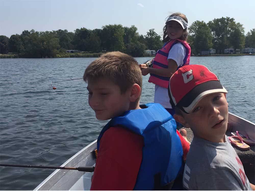 Three kids fishing from a boat at ROUNDUP LAKE CAMPGROUND