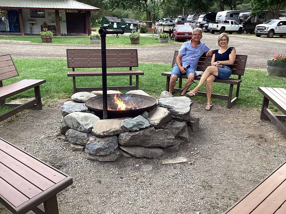 A couple sitting around a fire pit at WOLF LODGE CAMPGROUND