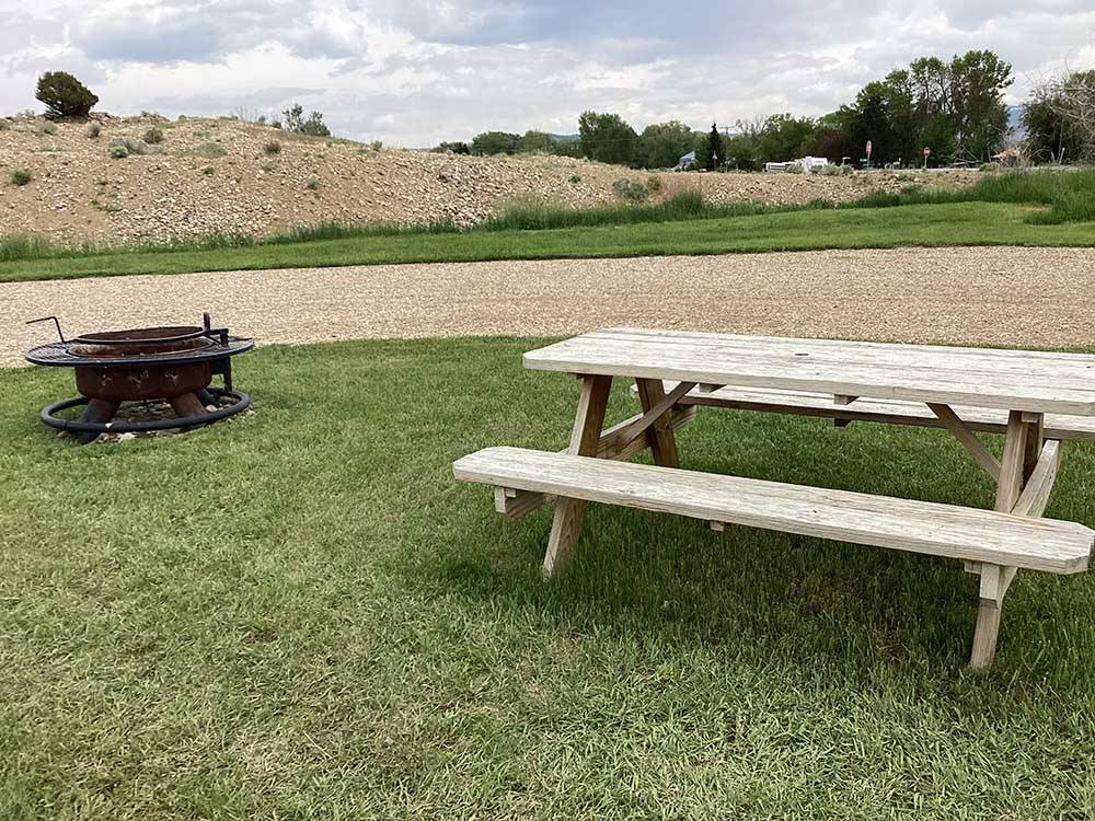 A picnic table and fire pit by a RV site at RUBY VALLEY CAMPGROUND & RV PARK
