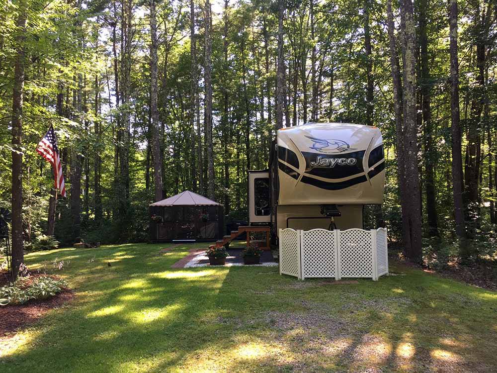  A fifth wheel trailer parked in a wooded RV site at WAKEDA CAMPGROUND