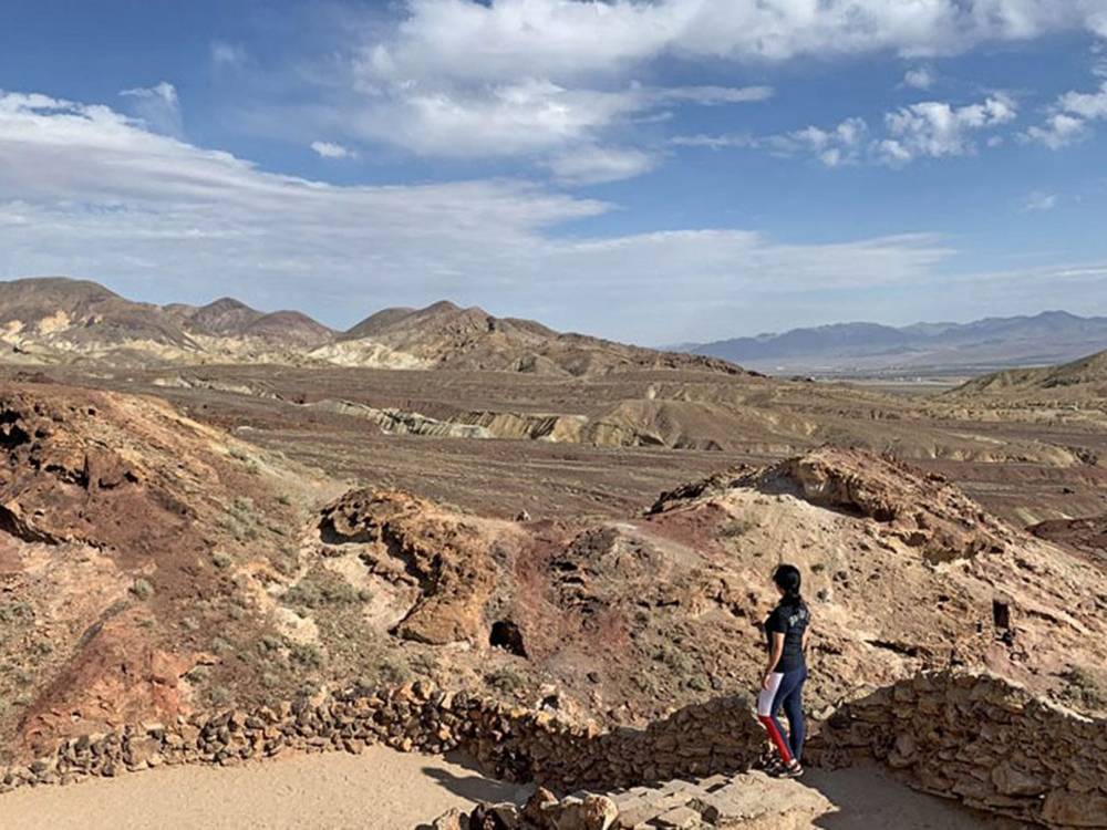 Woman hiking on a trail overlooking the view of mountains nearby