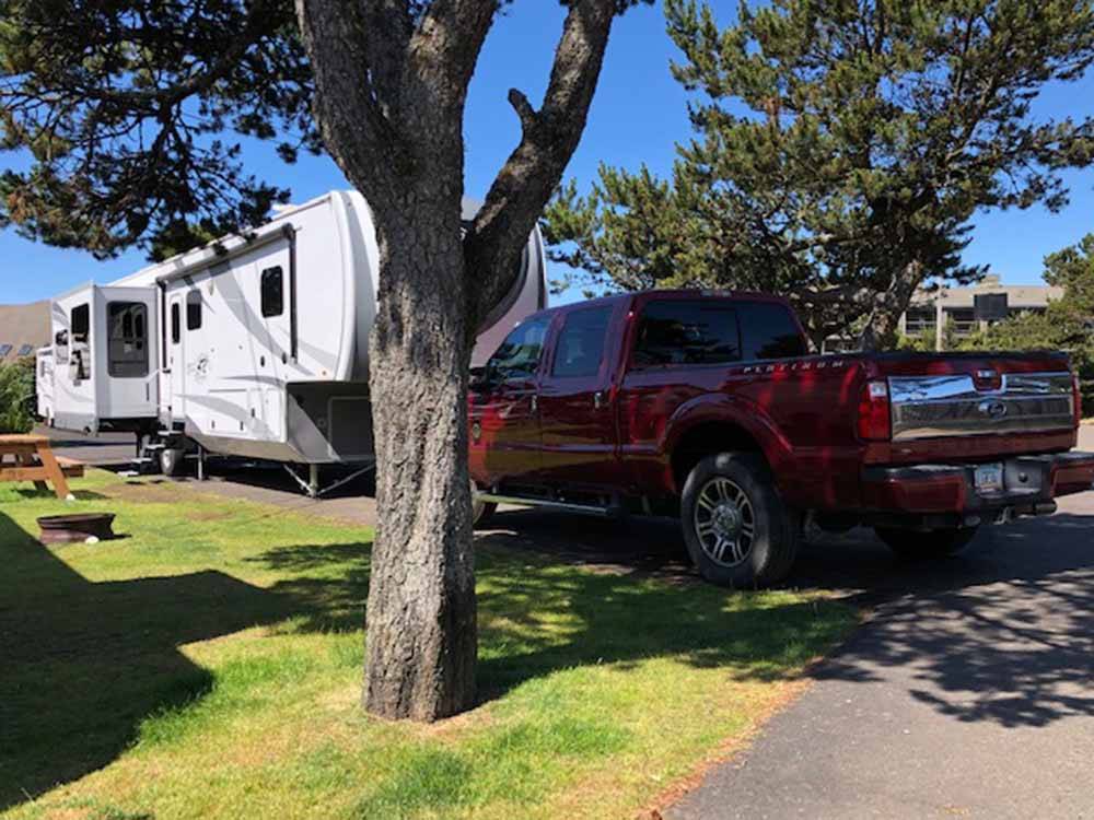 A fifth wheel and a pickup truck parked in an RV spot at CAPE KIWANDA RV RESORT & MARKETPLACE