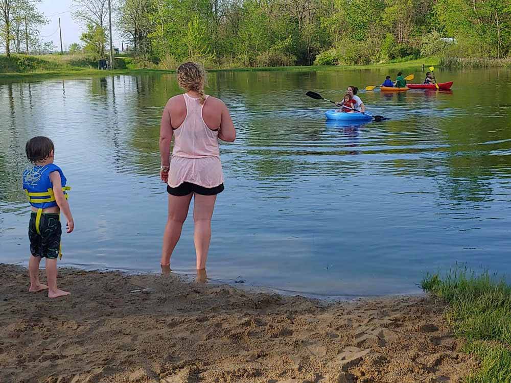 A lady and little boy standing by the lake watching people in kayaks at INDIAN CREEK CAMP & CONFERENCE CENTER