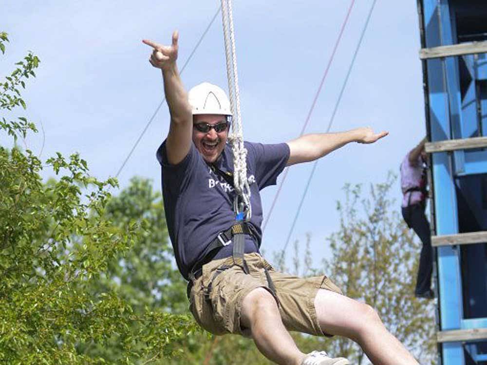 A man having fun on a zip line at INDIAN CREEK CAMP & CONFERENCE CENTER