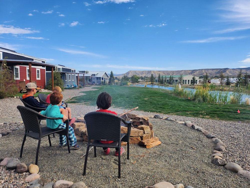 People in chairs by the water at MEADOWS OF SAN JUAN RV RESORT