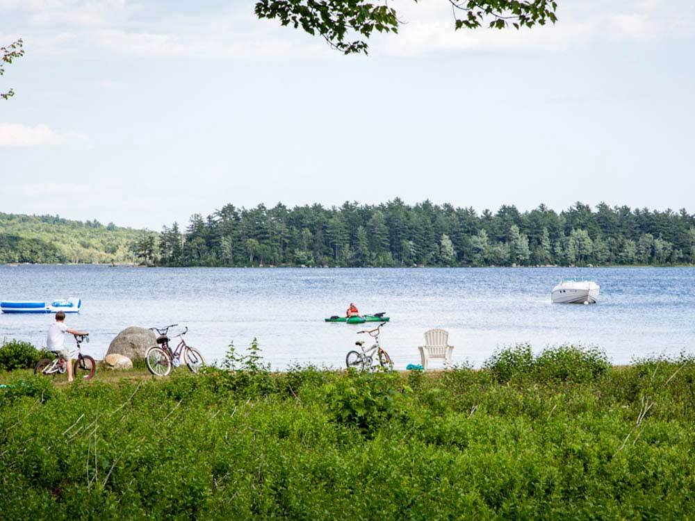 Kayaks and boat on the lake with bicycles on lake's edge at PATTEN POND CAMPING RESORT