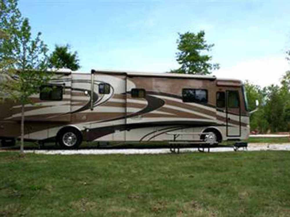 Tan Class A motorhome parked in gravel site at LAKESIDE RV PARK